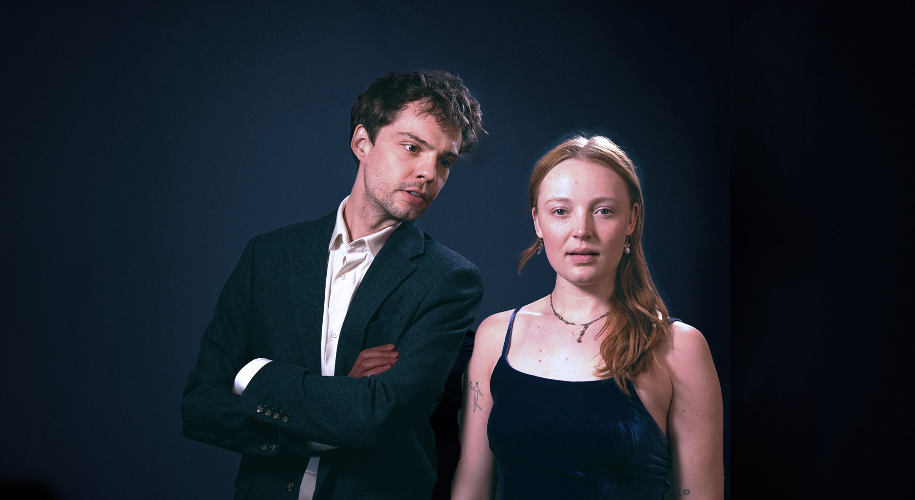 The duo "Mood Indigo" comprised of Tom Blake and Alice Pryor stand next to each other. Alice looks directly at camera while Tom looks slightly off to side.